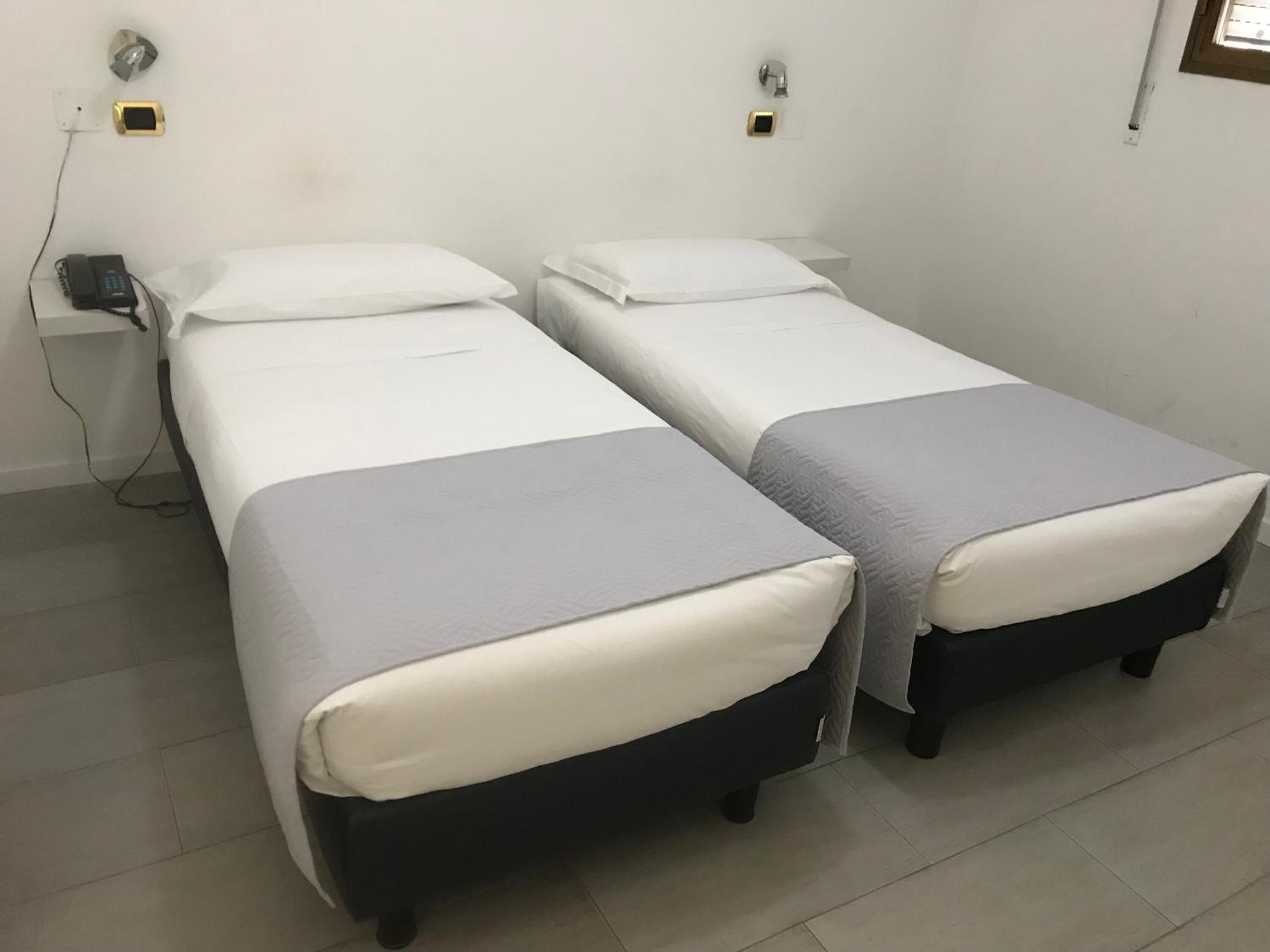 Ein Doppelzimmer mit zwei Einzelbetten, einem Nachttisch, einem Telefon und einer Steckdose.