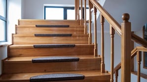 A wooden staircase with a handrail and a landing with a black mat. - Hotel Citadella Bucuresti (Bucharest)