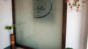A reception area with a frosted glass wall displaying the hotel's name, a potted plant, and a small table with a decorative item. - Hotel Citadella Bucuresti (Bucharest)
