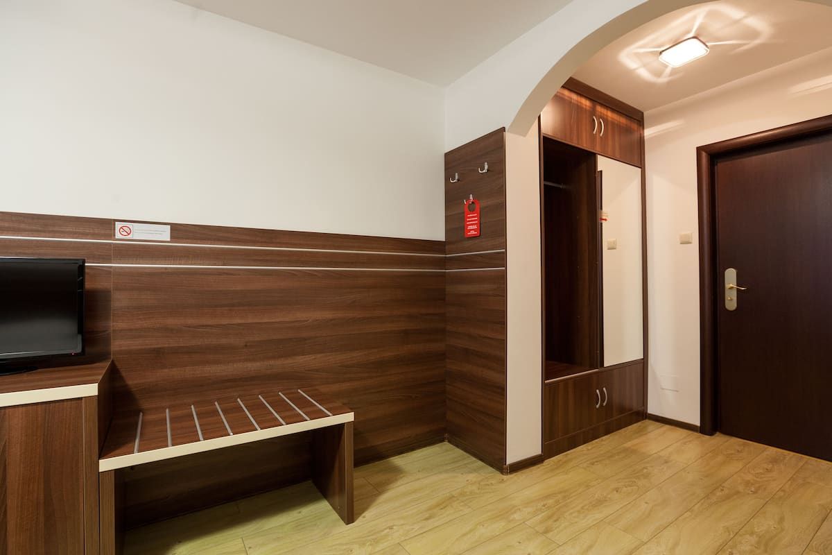 Habitación de esquina con banco empotrado, perchero y armario.