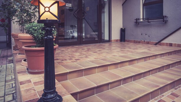 A set of outdoor steps leading to a building entrance, a potted plant, and a street lamp. - Hotel Citadella Bucuresti (Bucharest)