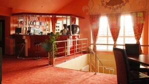 A bar area with a counter, stools, and a television. There is a staircase leading to a dining area with chairs and a table. - Pantex Hotel Brasov (Brasov)