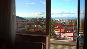 A room with a large window offering a view of a cityscape with buildings and greenery. - Pantex Hotel Brasov (Brasov)