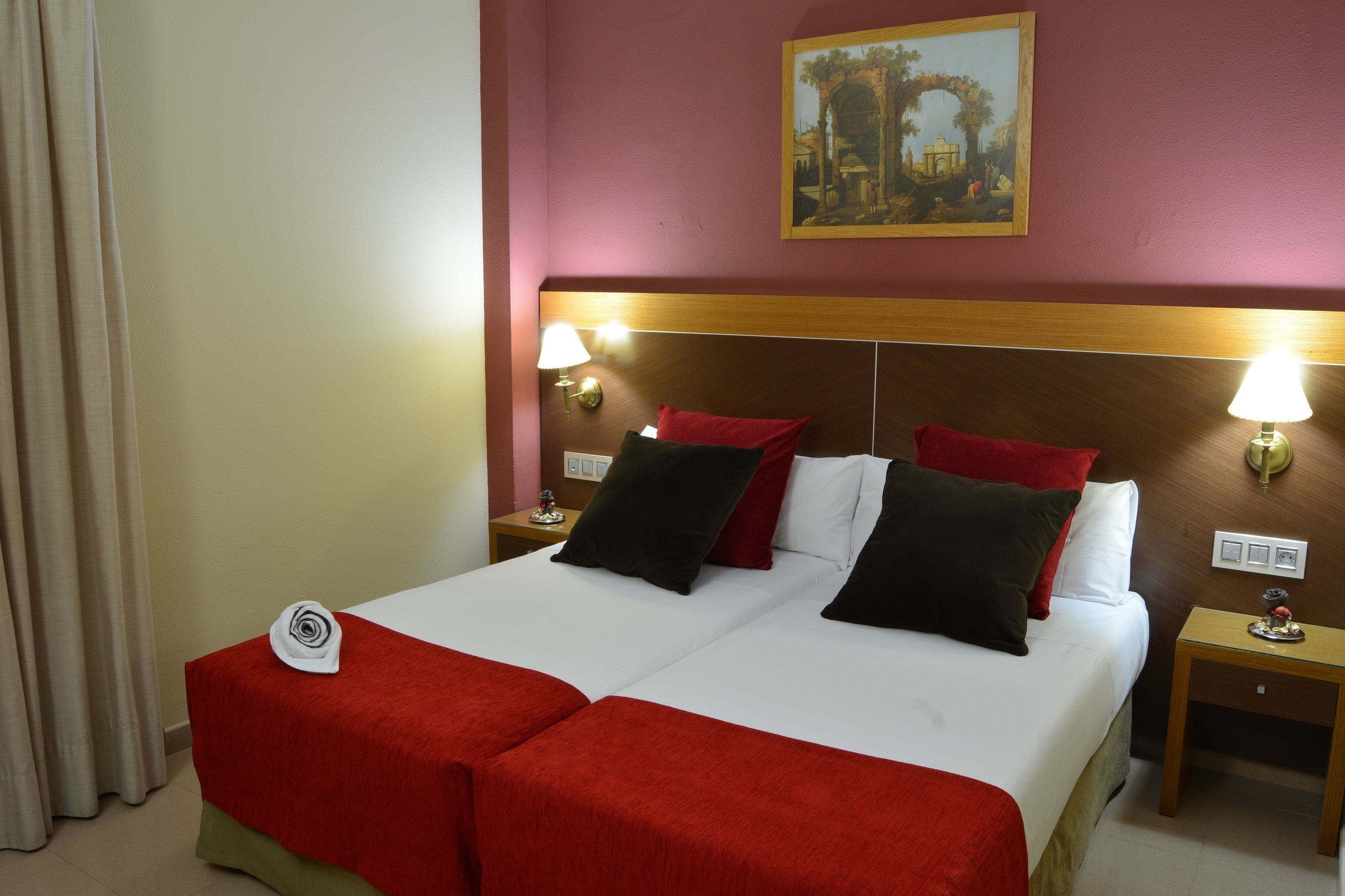 Een hotelkamer met een bed, twee nachtkastjes en een schilderij aan de muur.