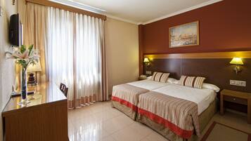 Una camera d'albergo con un letto, comodini, una scrivania e una sedia.