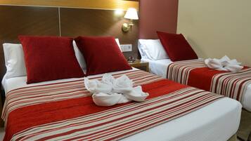 A hotel room with two beds, each with red and white striped bedding, and a headboard with a light fixture.