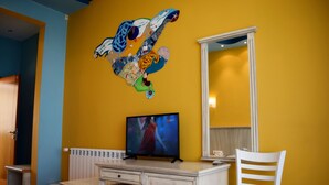 A room with a bed, a desk, a chair, a television, and a colorful wall decoration. - Brigantina Beach (Varna)
