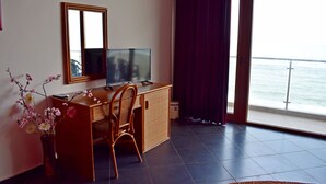 A room with a desk, chair, TV, and a view of the sea through a large window. - Brigantina Beach (Varna)