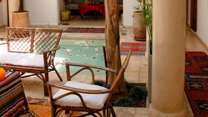 Un amplio patio interior con piscina, mobiliario de bambú y plantas en macetas.