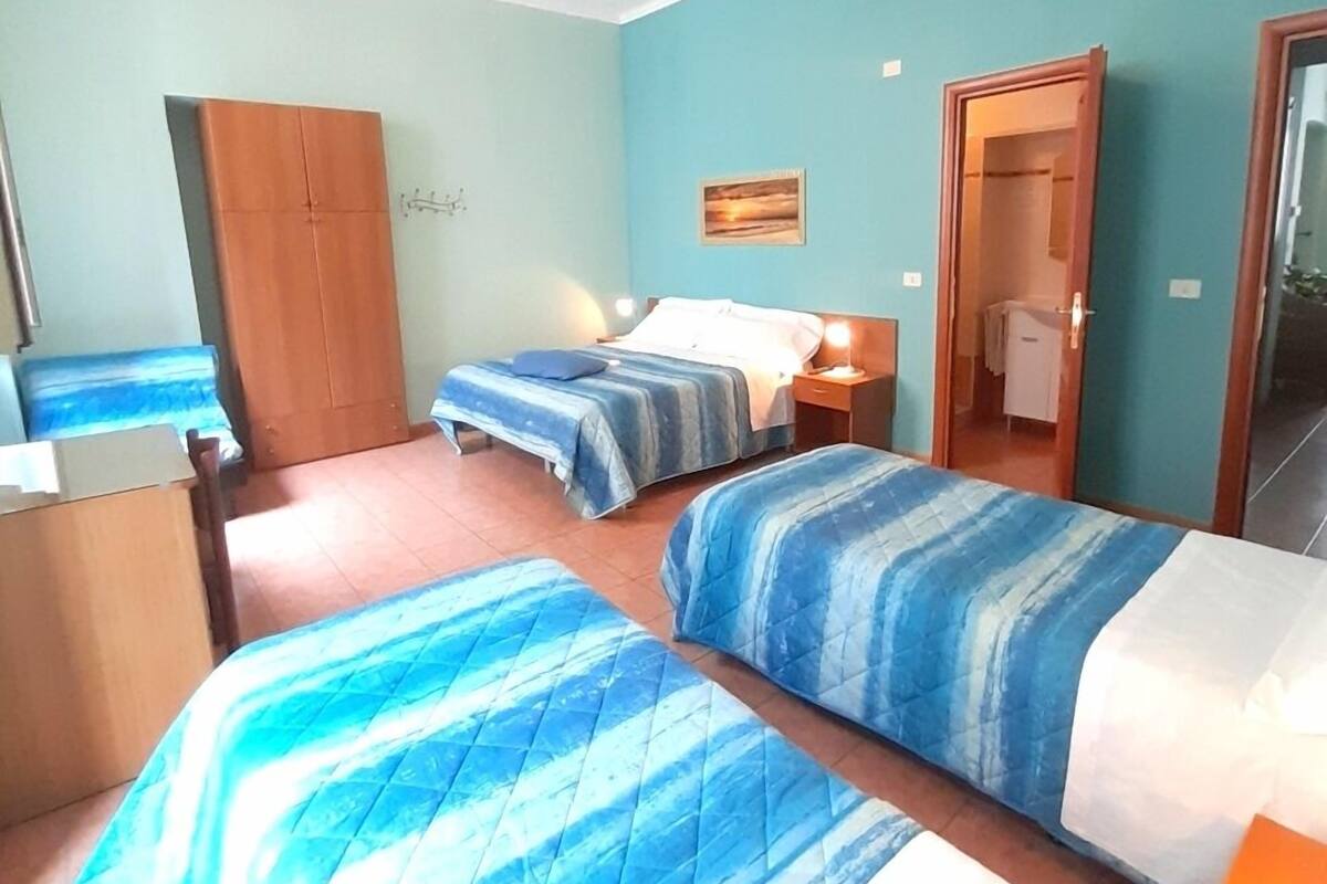Una habitación con dos camas, un armario, un escritorio y un espejo.