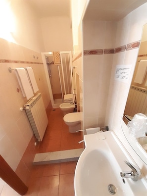 A bathroom with a bathtub, toilet, and shower area. - Albergo Alba (Turin)