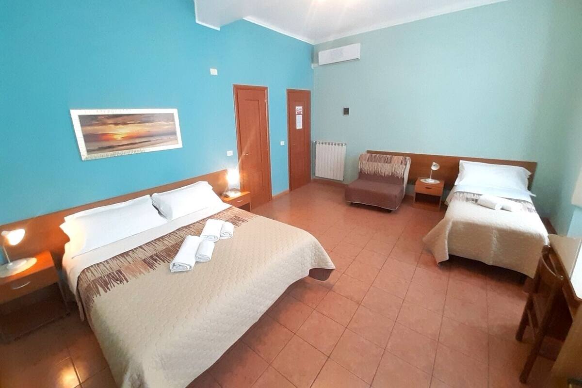 Habitación de hotel con dos camas, un cuadro en la pared y una ventana con cortinas.