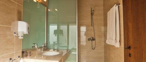 A modern bathroom with a large mirror, dual sinks, a glass-enclosed shower, and a wooden door.