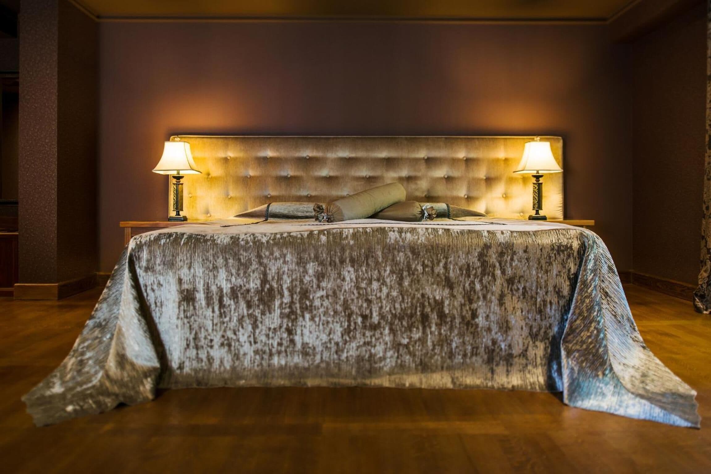 A bed with a tufted headboard, two bedside lamps, and a textured bedspread.