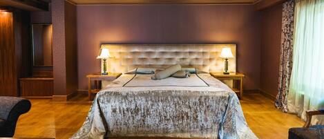 A spacious bedroom with a large bed, two bedside tables, and a headboard with a tufted design.