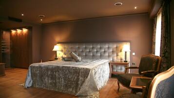 A bedroom with a large bed, a tufted headboard, bedside lamps, a wooden nightstand, and a chair.
