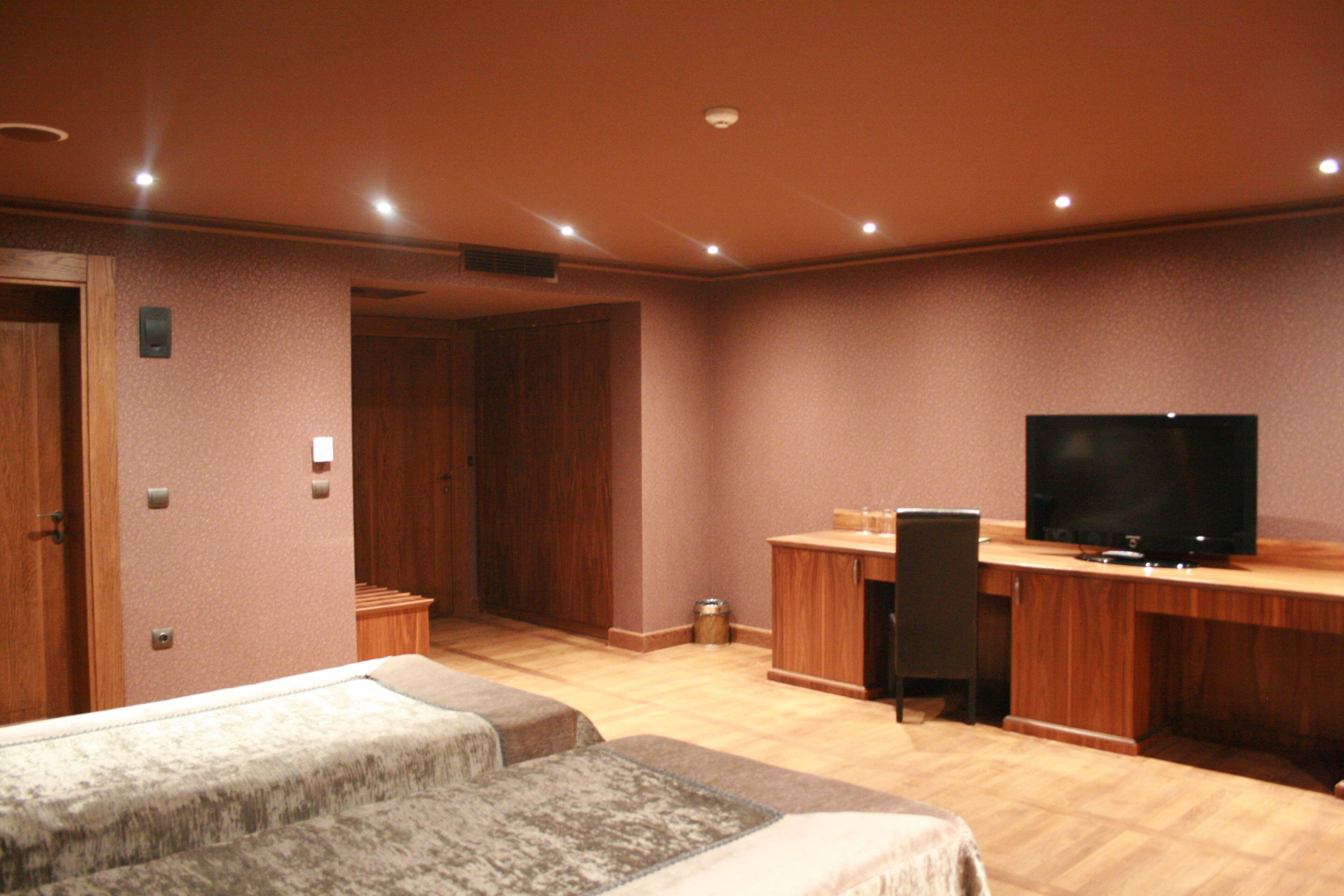 A hotel room with a wooden desk, a television, and two beds.