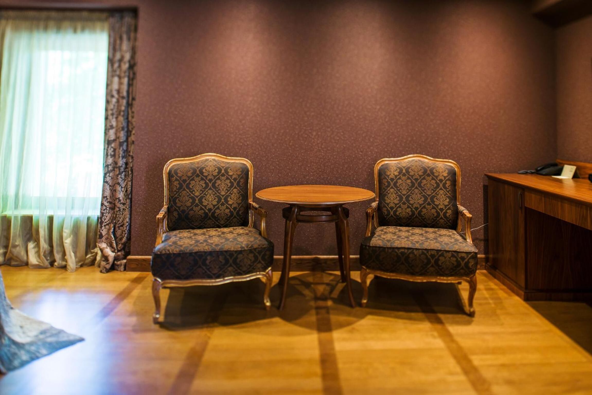 Une pièce comprenant deux fauteuils à motifs et une petite table ronde.