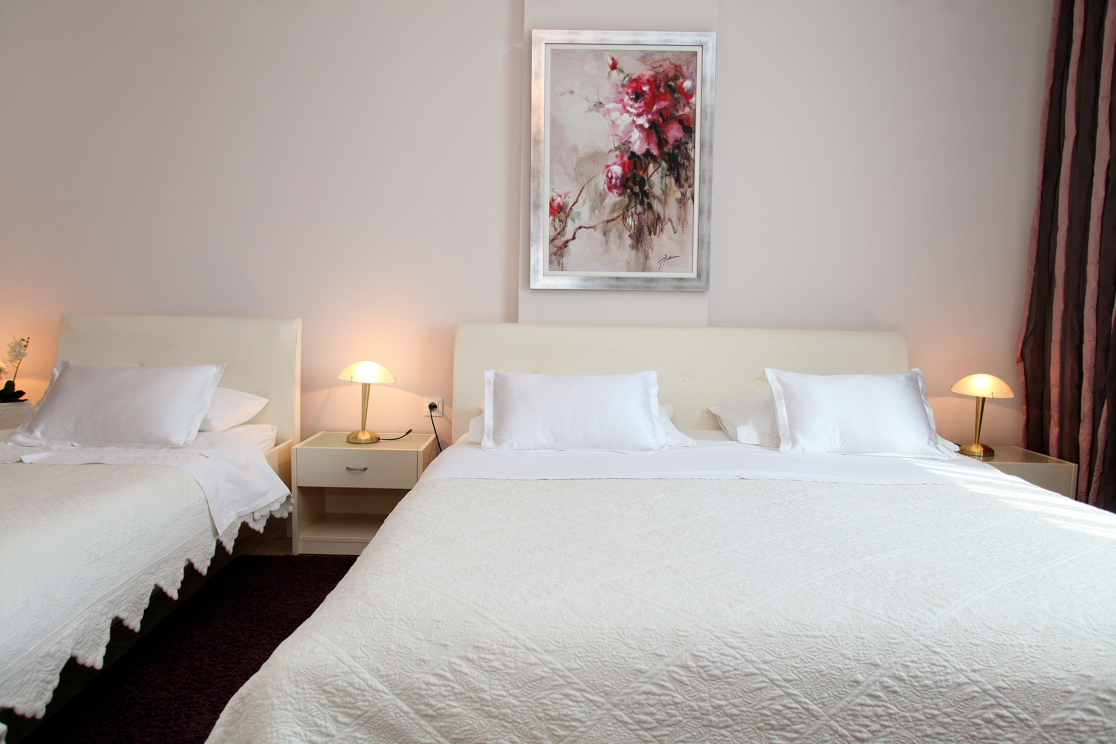 A hotel room with two beds, a large painting on the wall, and bedside lamps.