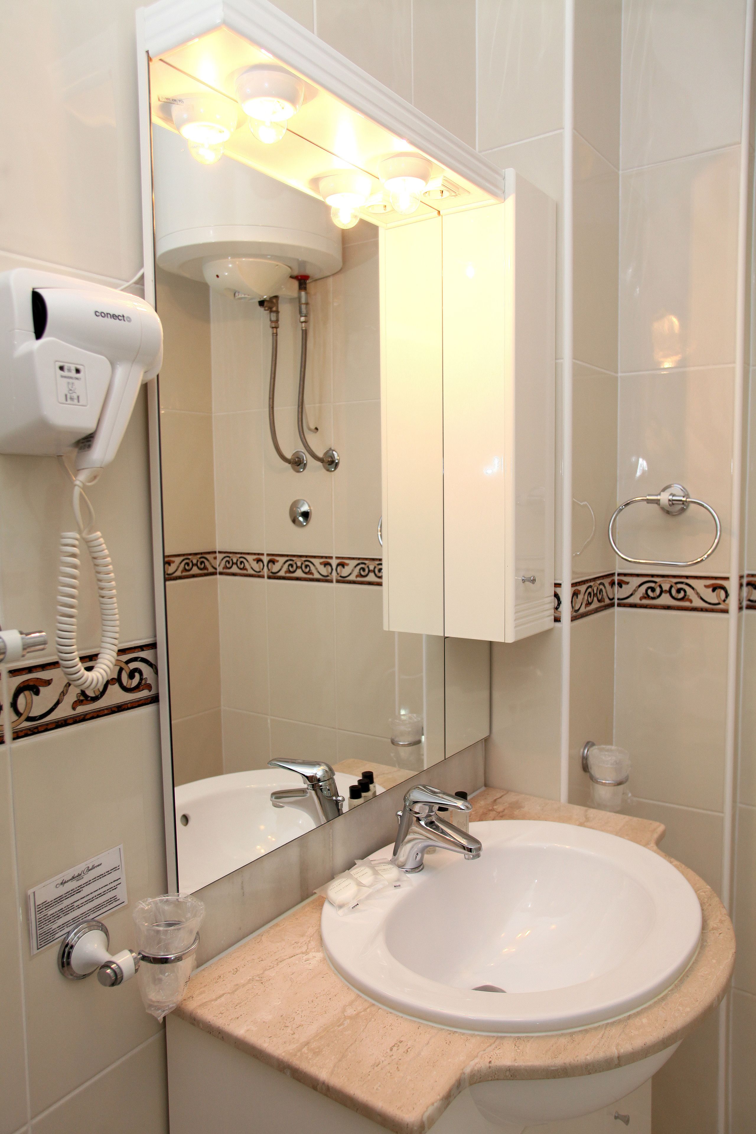 A bathroom with a sink, mirror, hairdryer, and towel rack.