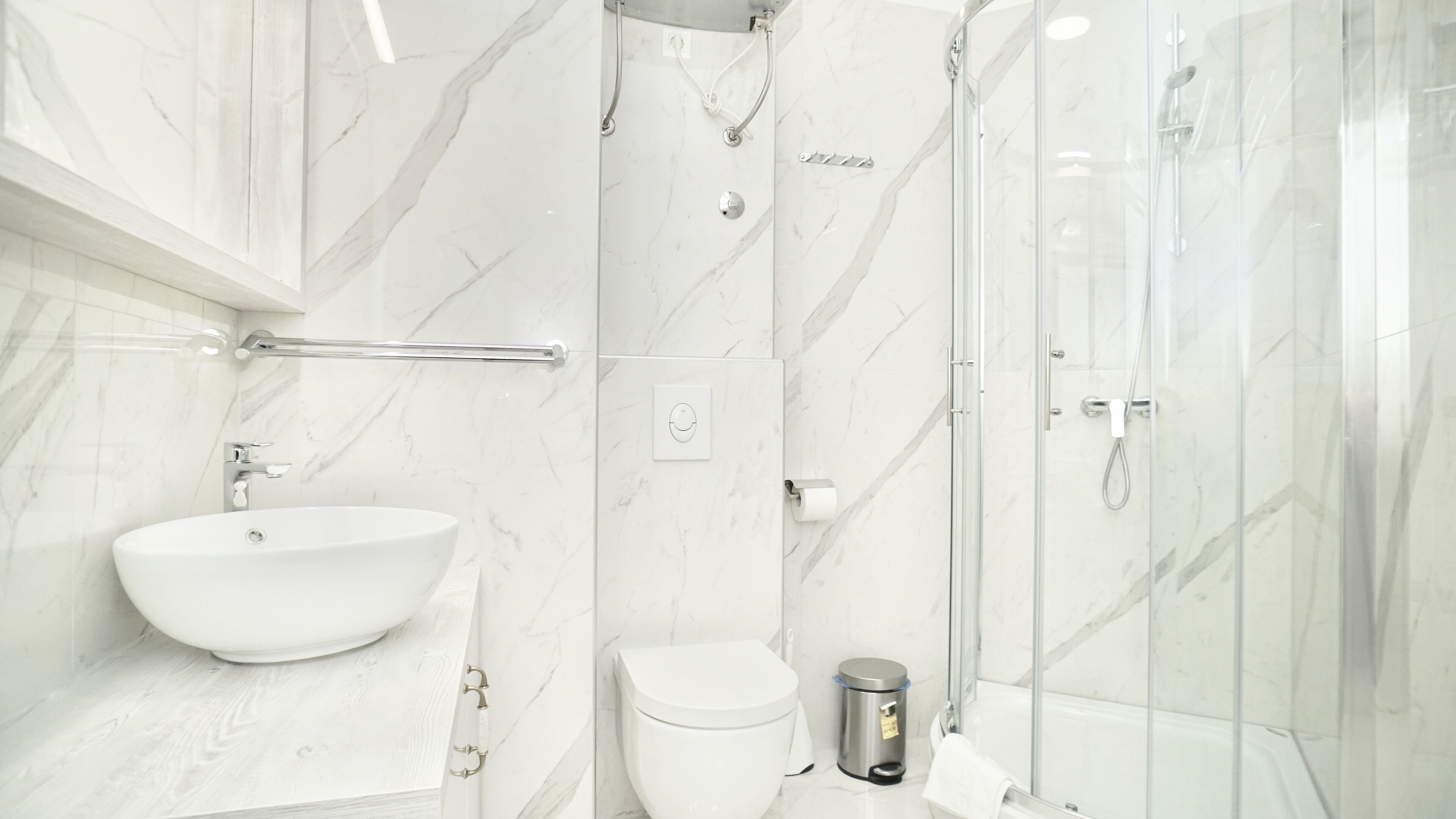 A modern bathroom with a marble sink, toilet, and shower.