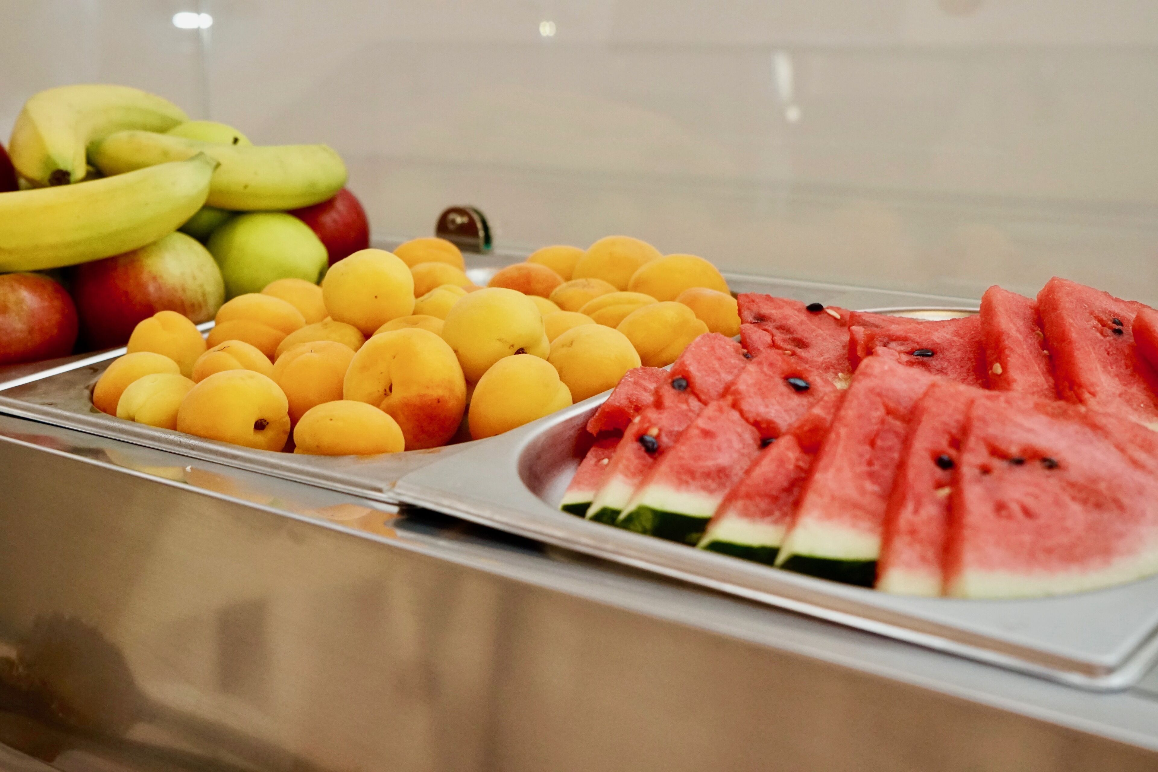 A fruit display with bananas, apples, lemons, and watermelon slices.