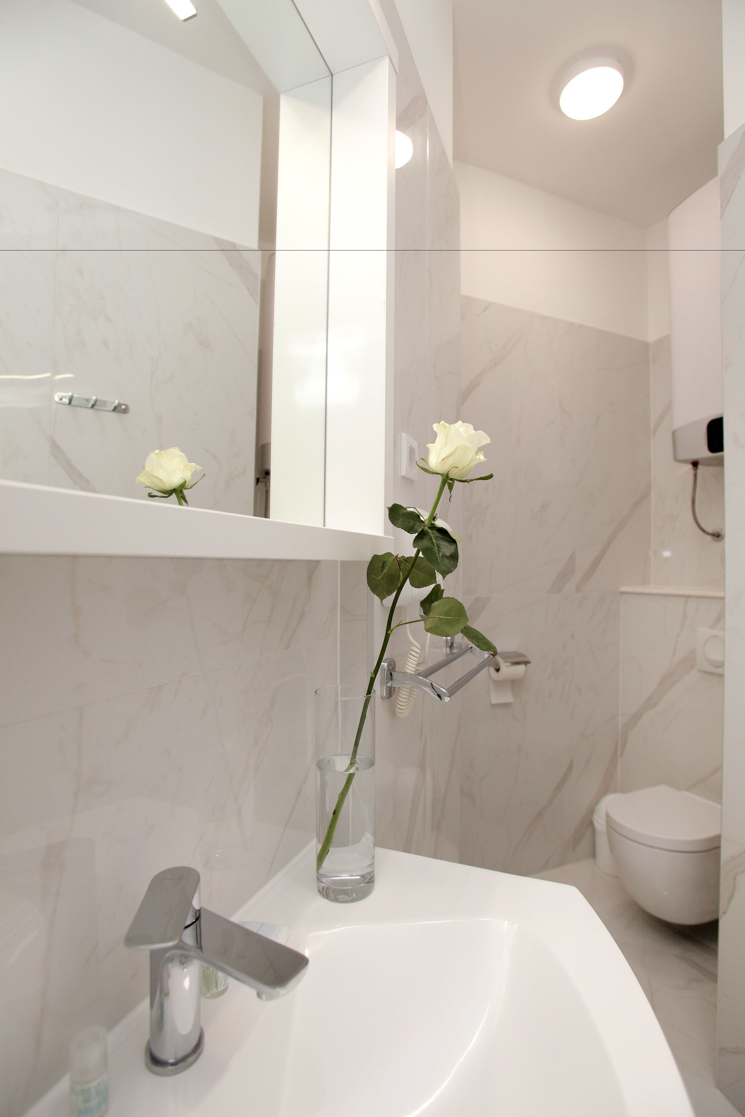 A bathroom with a white sink, a mirror, and a toilet.