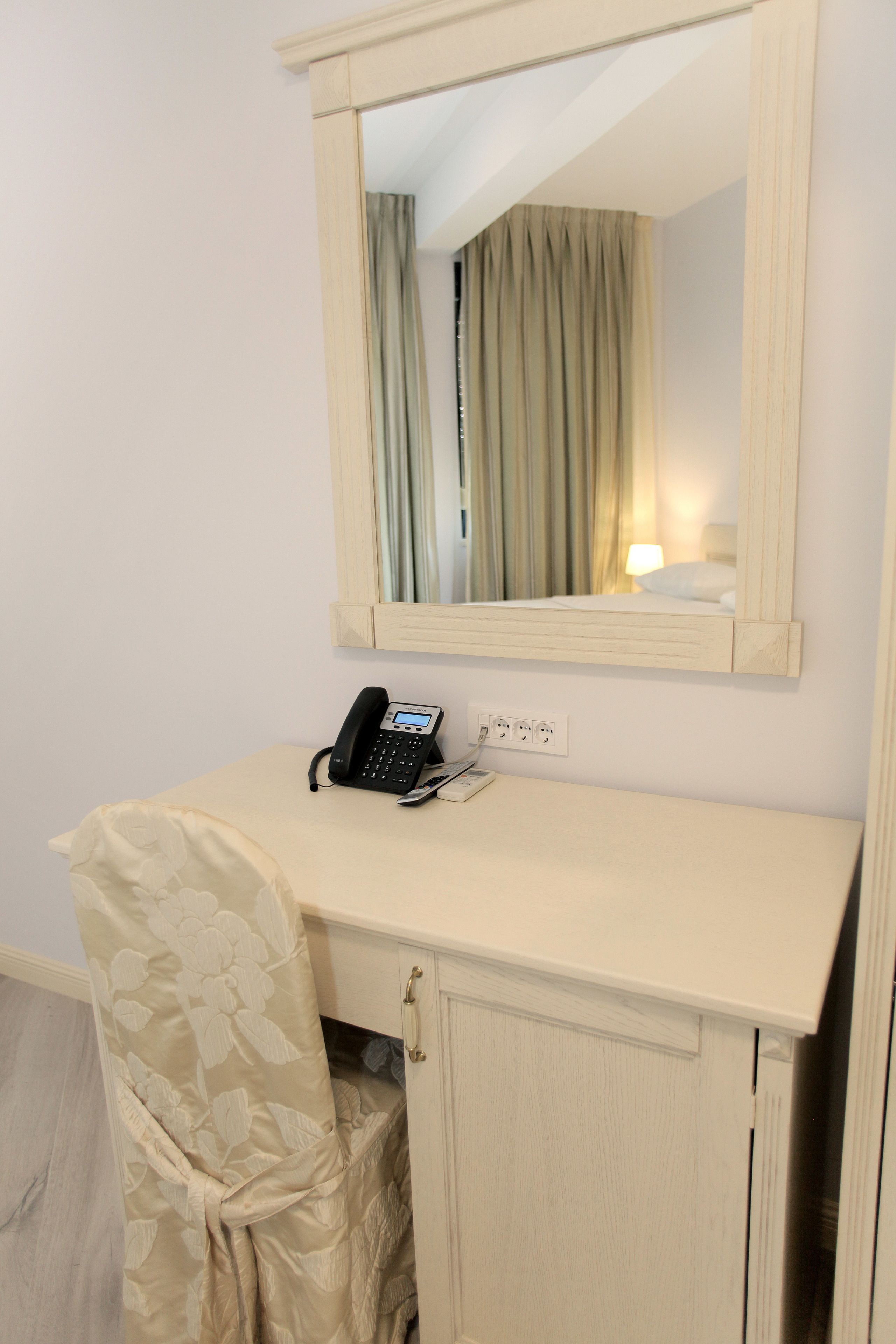 Ein kleiner, privater Arbeitsraum mit Schreibtisch, Telefon und einem Spiegel darüber.