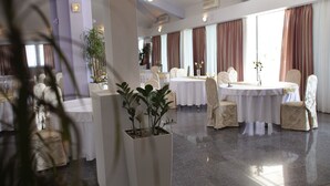 Un amplio comedor de hotel con mesas redondas, manteles blancos y sillas color beige.