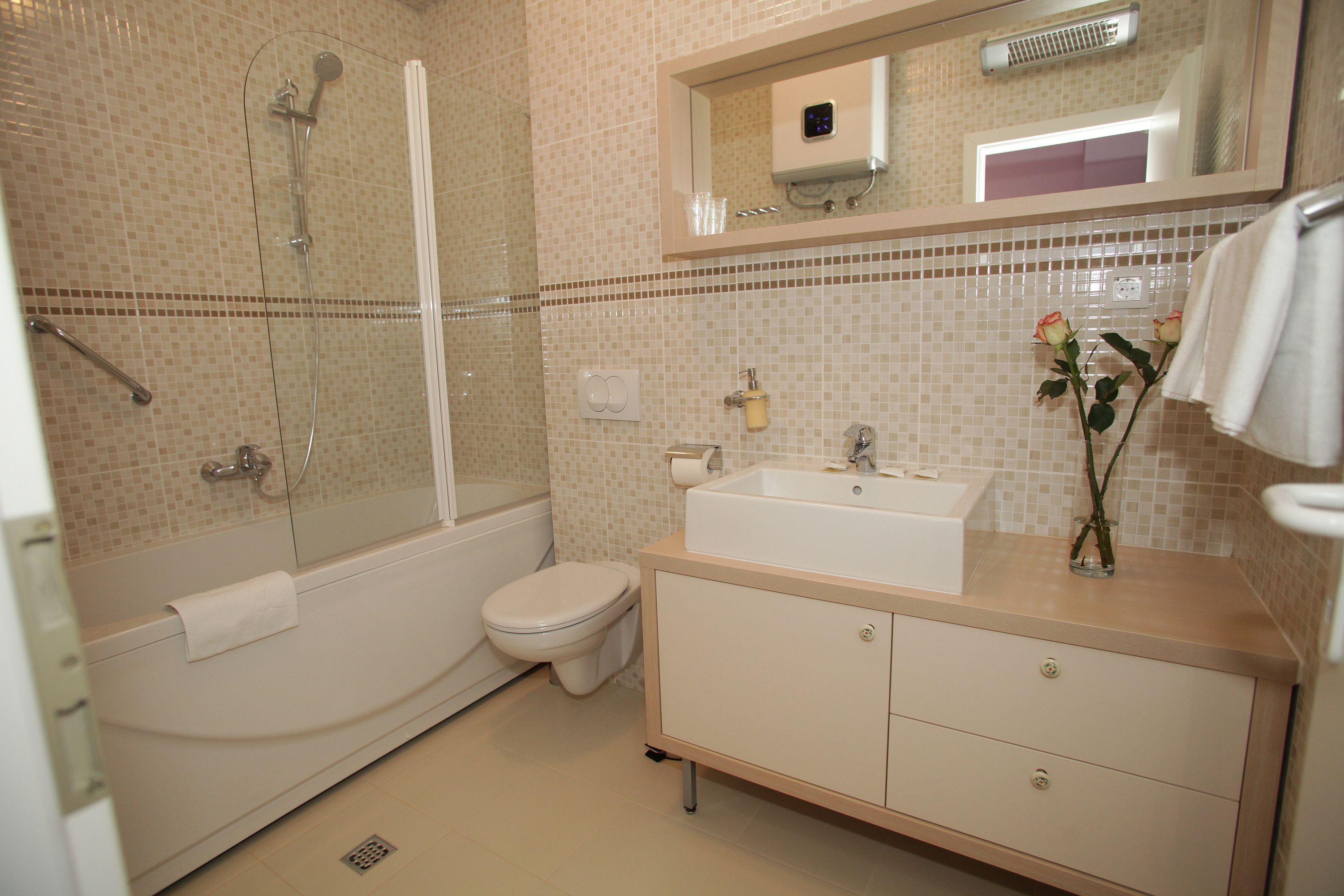 Un bagno con vasca, WC, lavandino e specchio sopra il lavandino.