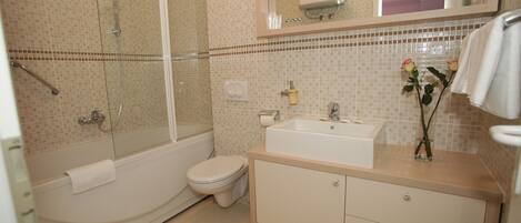 A bathroom with a bathtub, toilet, sink, and a mirror above the sink.