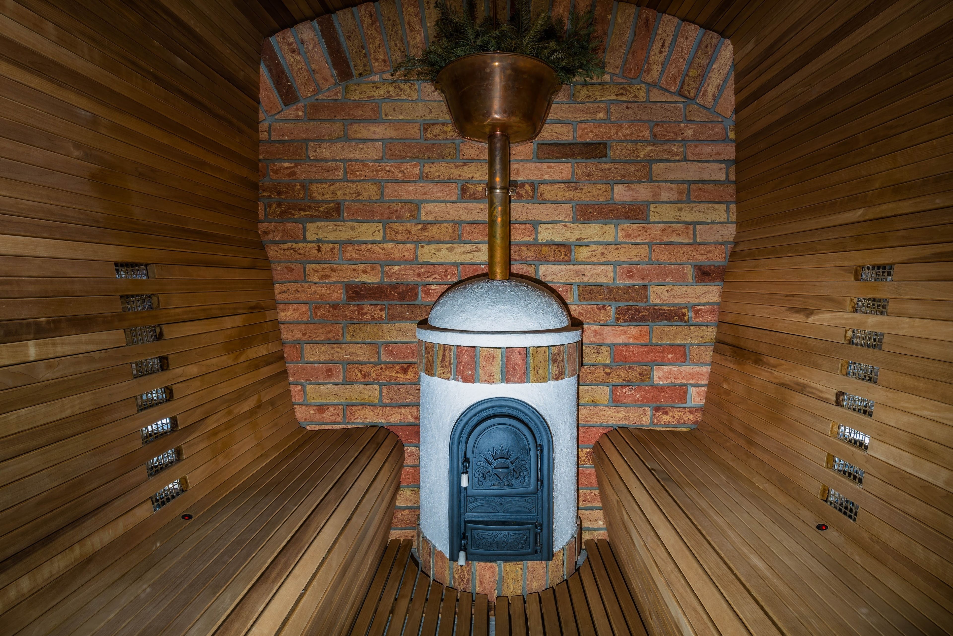 Una sauna con parete in mattoni, una panca di legno e una porta metallica.