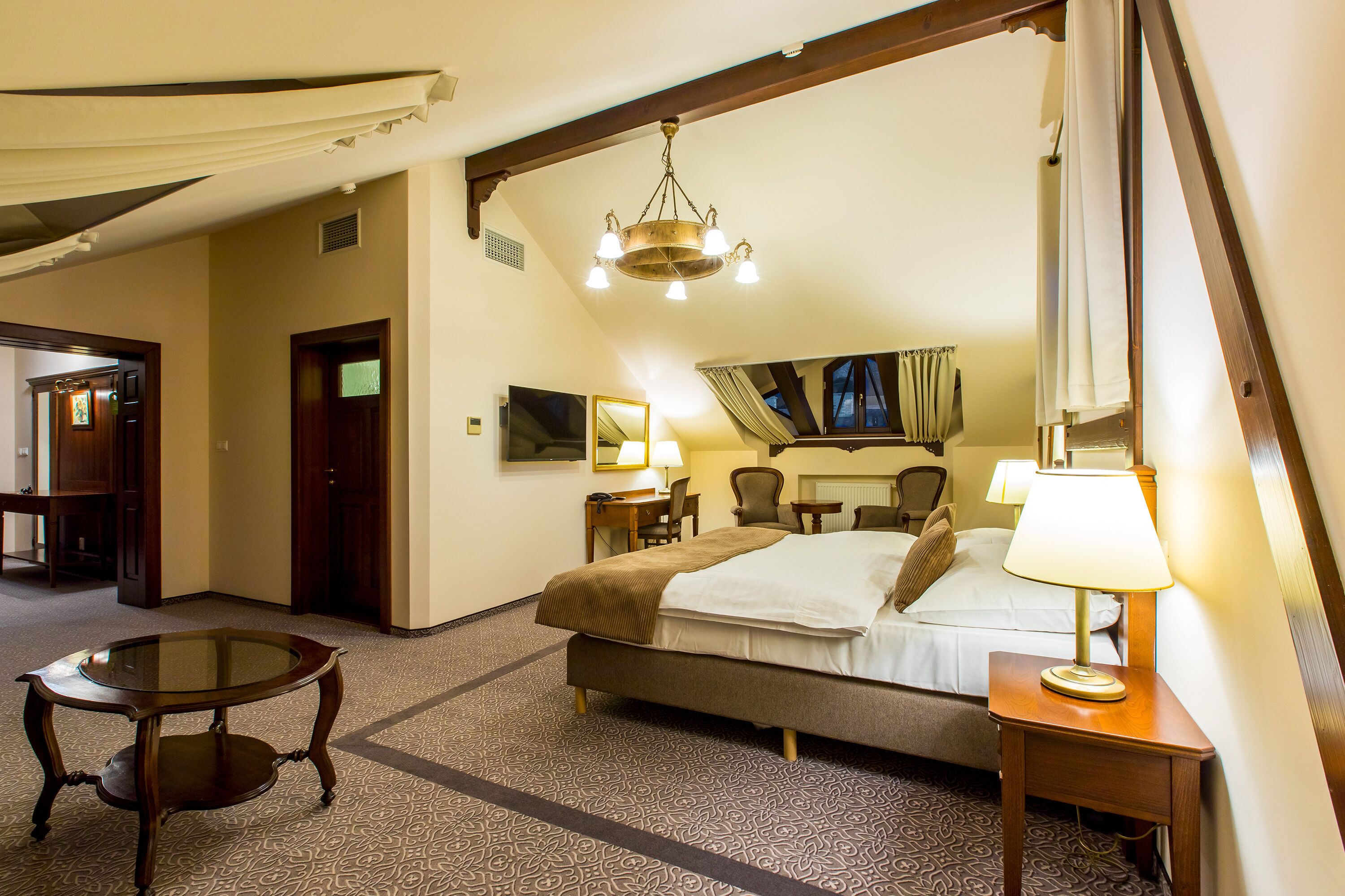 A hotel room with a bed, bedside table, lamp, and a small round table.