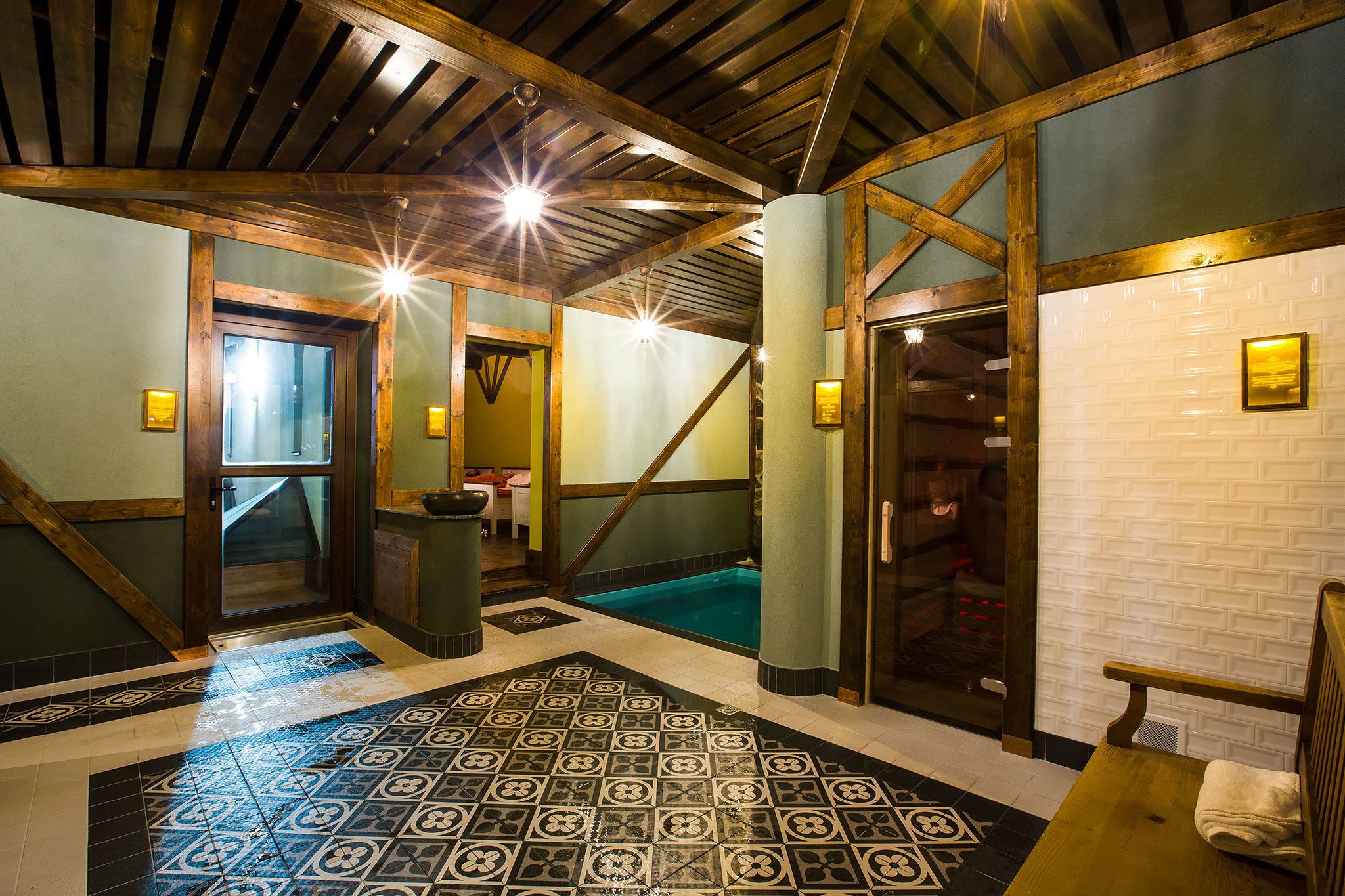 A hotel lobby with a tiled floor, wooden beams, and a pool area.