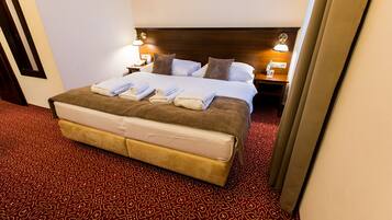 A hotel room with a large bed, two bedside tables with lamps, and a patterned carpet.
