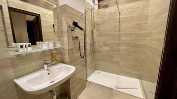 A modern bathroom with a glass-enclosed shower, a white sink, and a mirror above it.