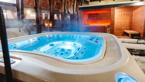 Un jacuzzi en una cabaña de madera con chimenea a la vista y una zona de estar acogedora.