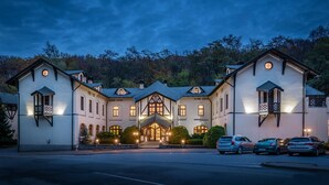 A large, multi-story building with a symmetrical facade, multiple windows, and a central entrance with a decorative roof. - Hotel Bankov (Kosice)