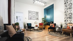 A modern living room with a wooden floor, black and brown chairs, a coffee table, and a blue accent wall. - Maverick Downtown (Budapest)