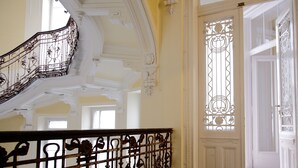 A grand staircase with ornate metal railings and a decorative glass door with intricate patterns. - Maverick Downtown (Budapest)