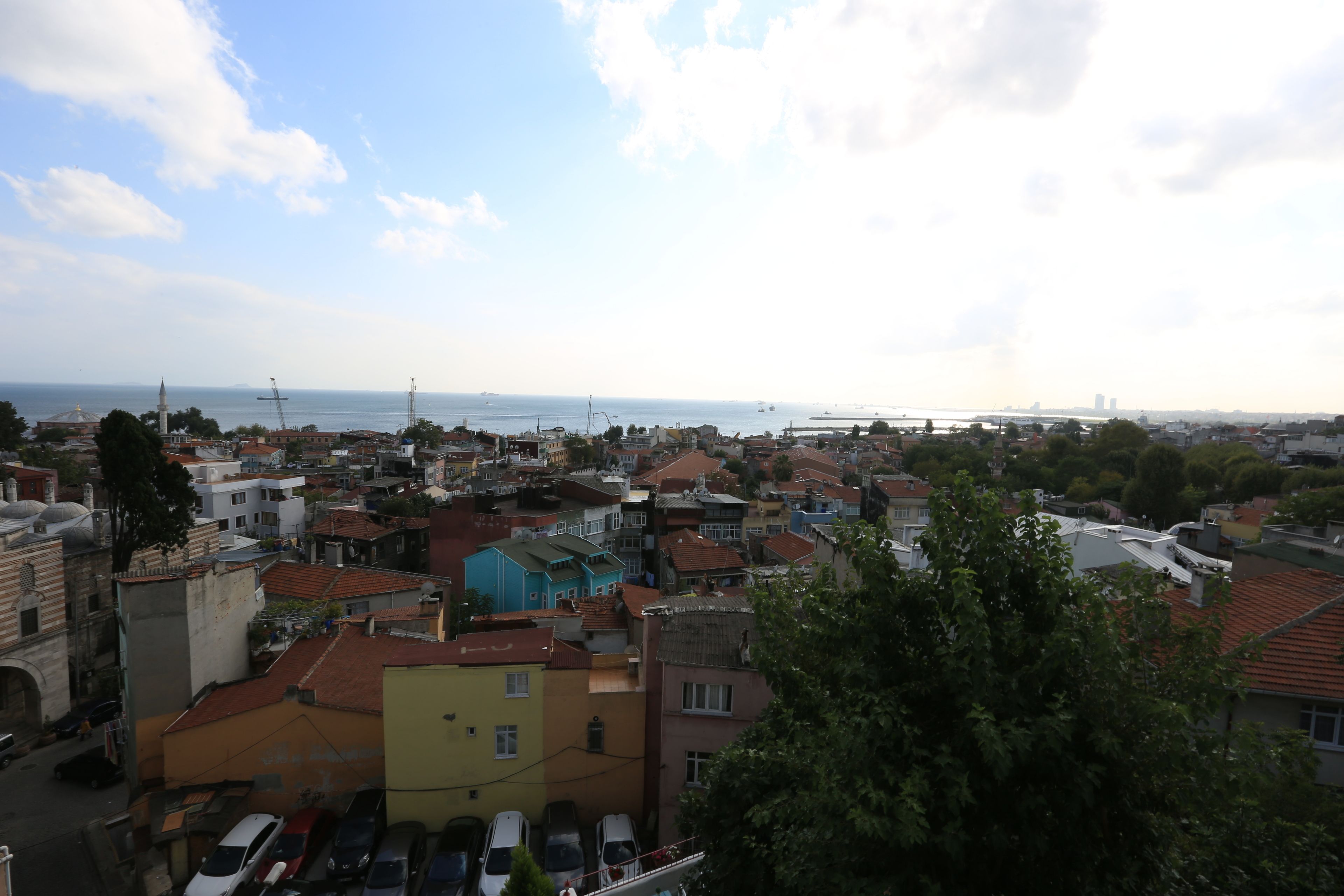 A densely packed urban area with buildings, a body of water, and a bridge in the distance.