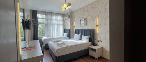 A hotel room with two beds, a desk, and a wardrobe.