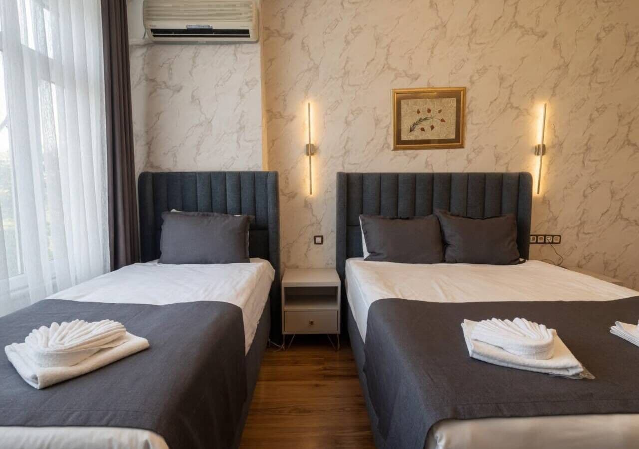 Habitación de hotel con dos camas, pared con diseño de mármol y un cuadro enmarcado.