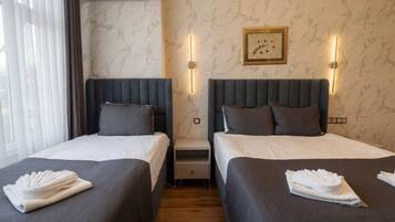 Habitación de hotel con dos camas, pared con diseño de mármol y un cuadro enmarcado.