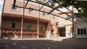 A building with a covered entrance, potted plants, and a gated area. - Vigor Hotel (Novi Sad)