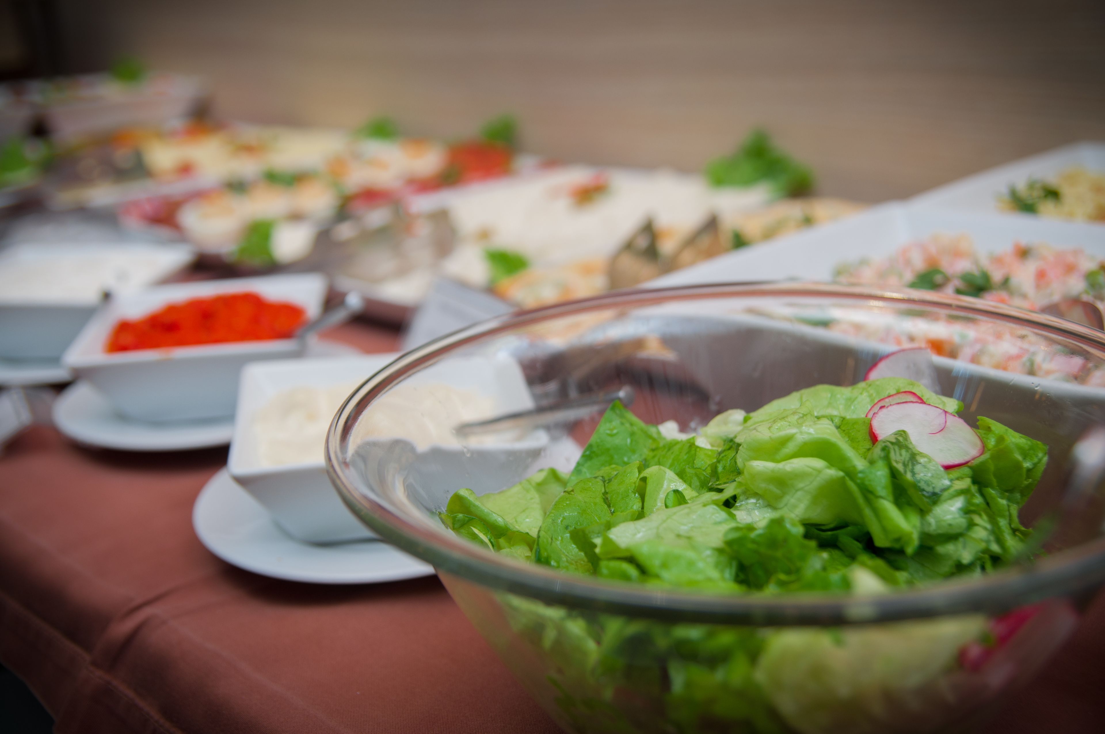 Een buffettafel met diverse gerechten, waaronder een grote saladeschaal op de voorgrond.