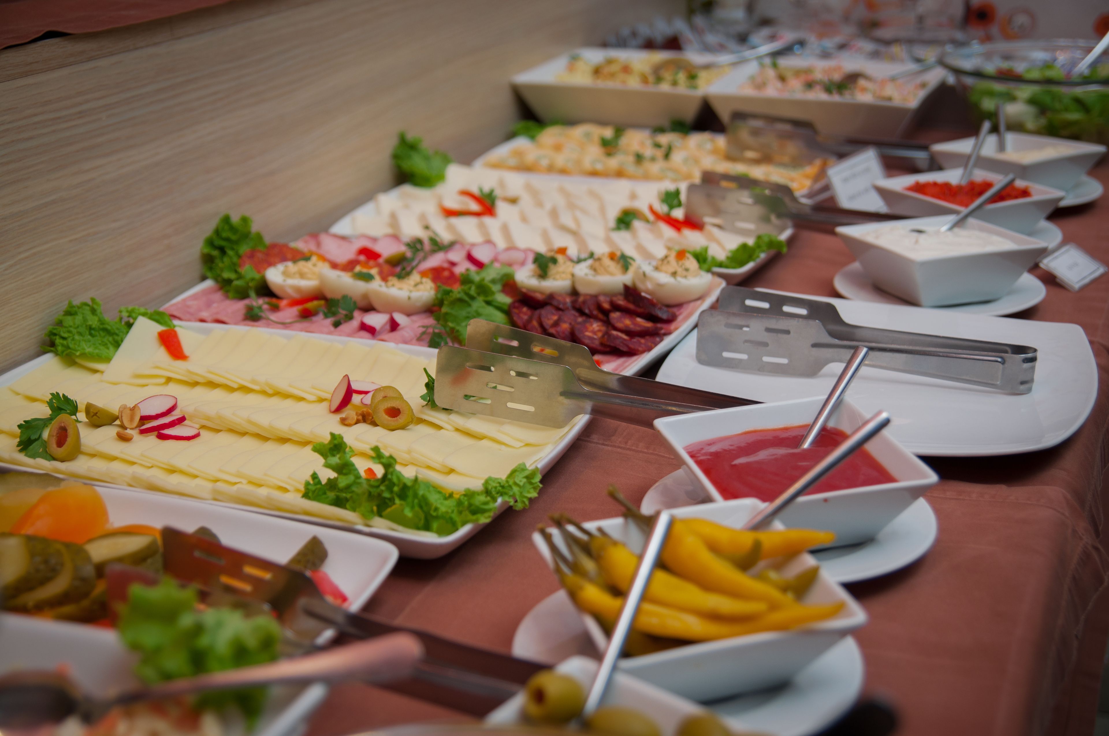 A buffet table with various food items and utensils.