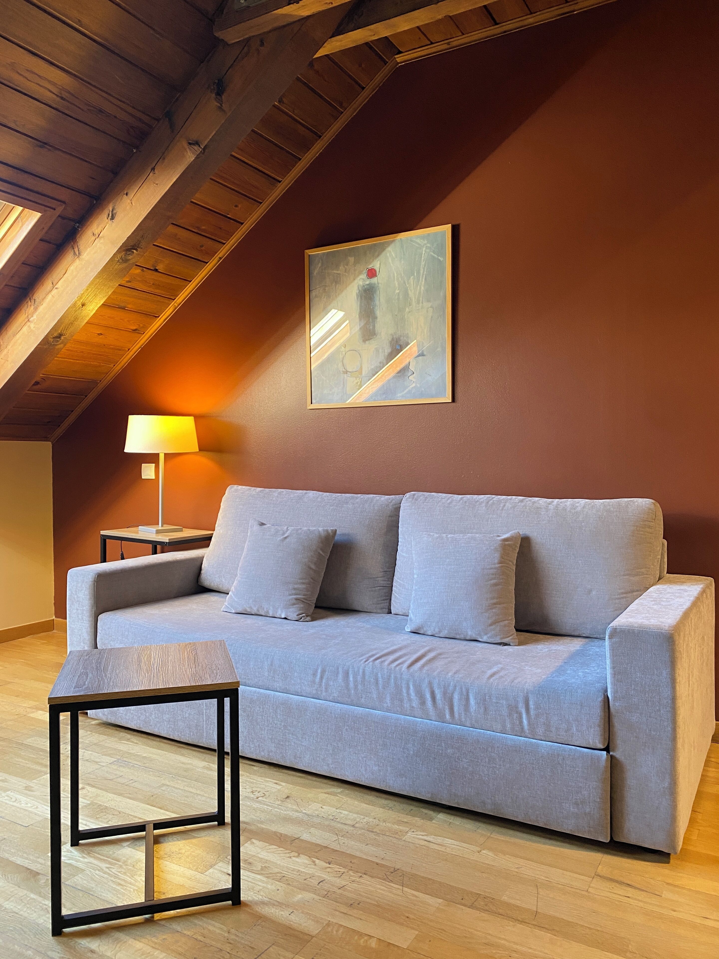 Una sala moderna con un sofá gris, una mesita y una lámpara.