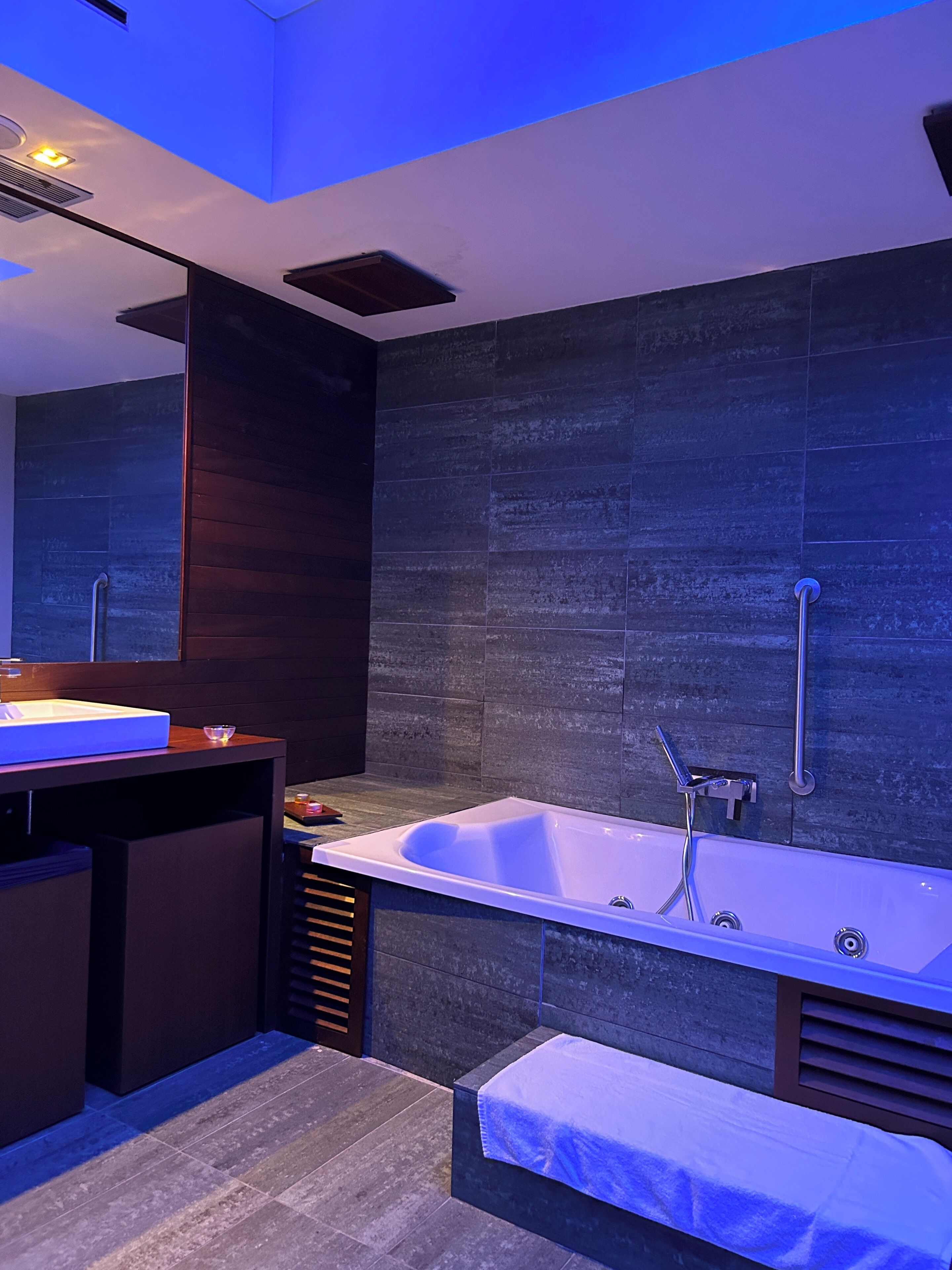 Un baño moderno con una bañera grande, un tocador con espejo y un banco.