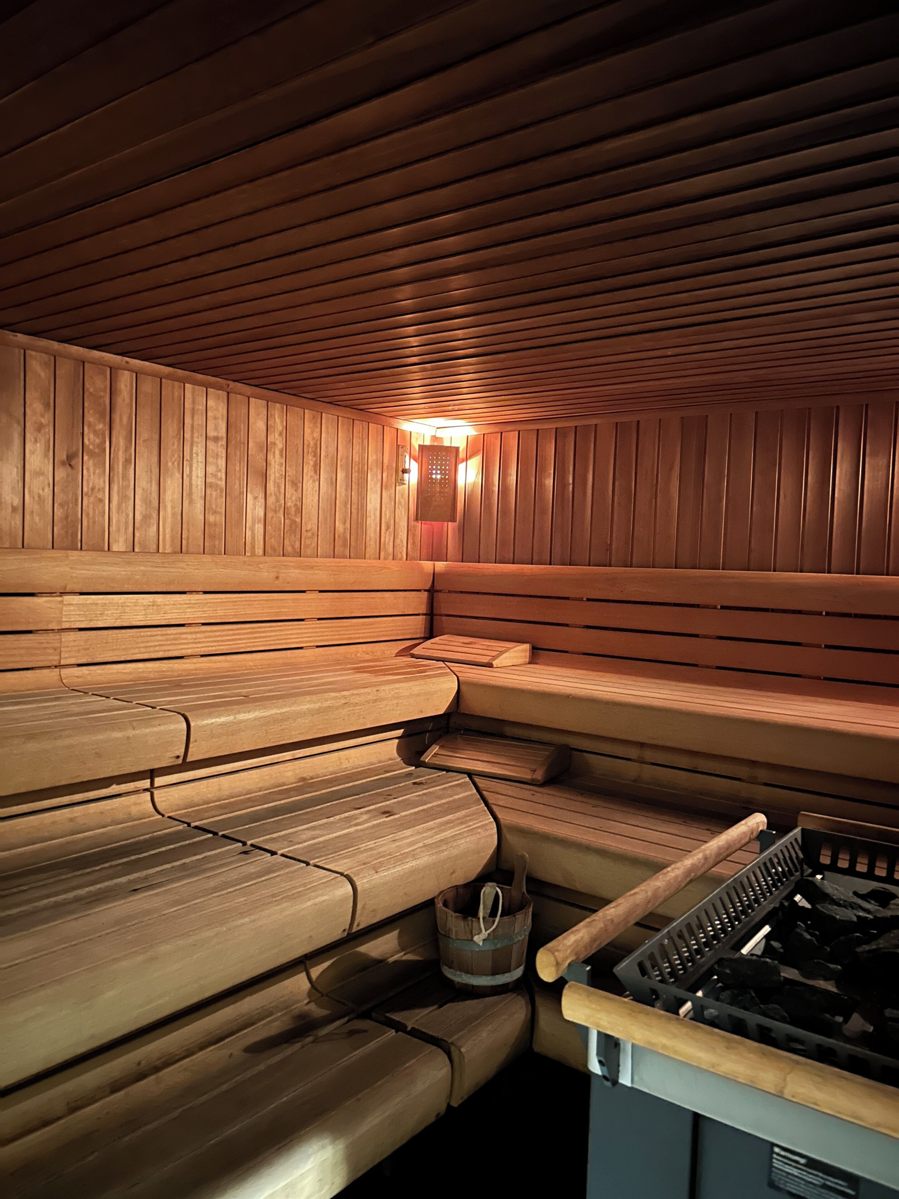 A sauna with wooden benches and a visible sauna heater.